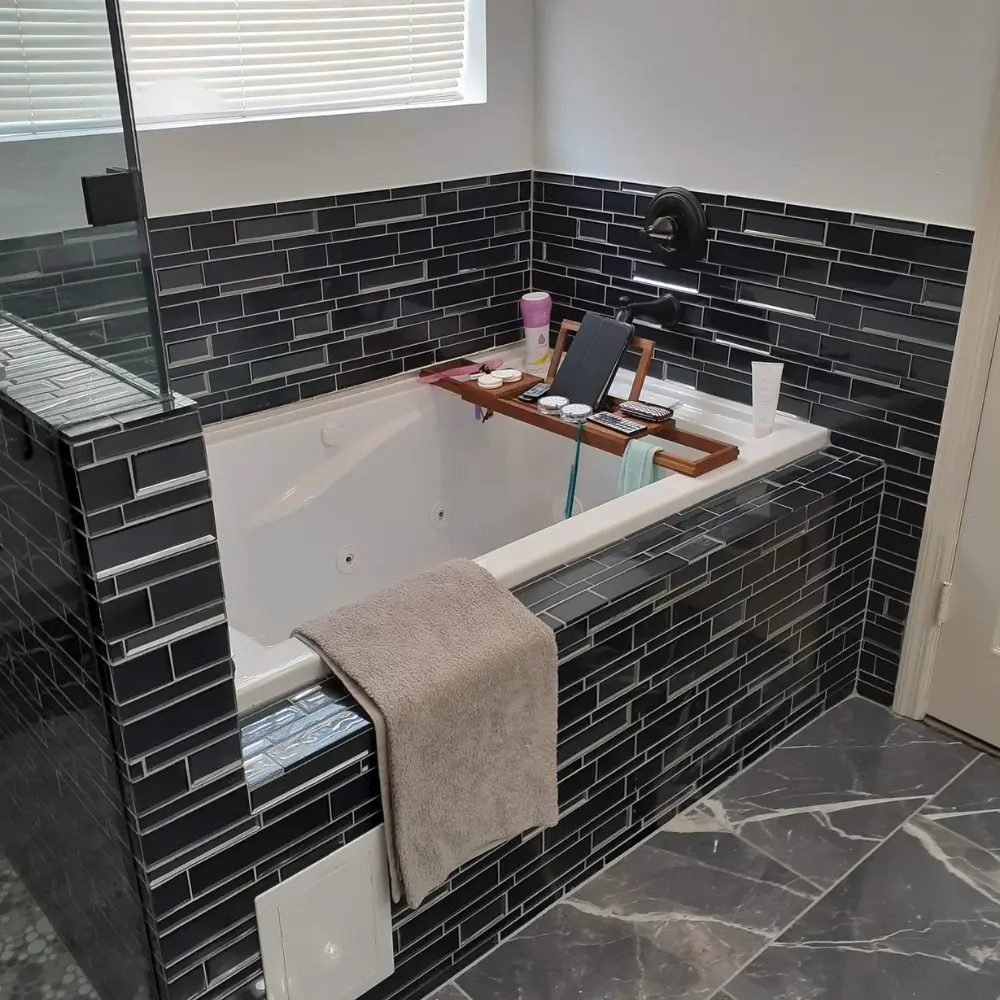 Modern bathtub with dark subway tile surround and wooden tray