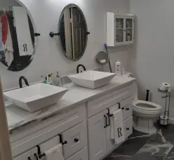 Modern bathroom with dual sinks, oval mirrors, and white cabinetry