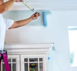 Person painting a ceiling with a roller