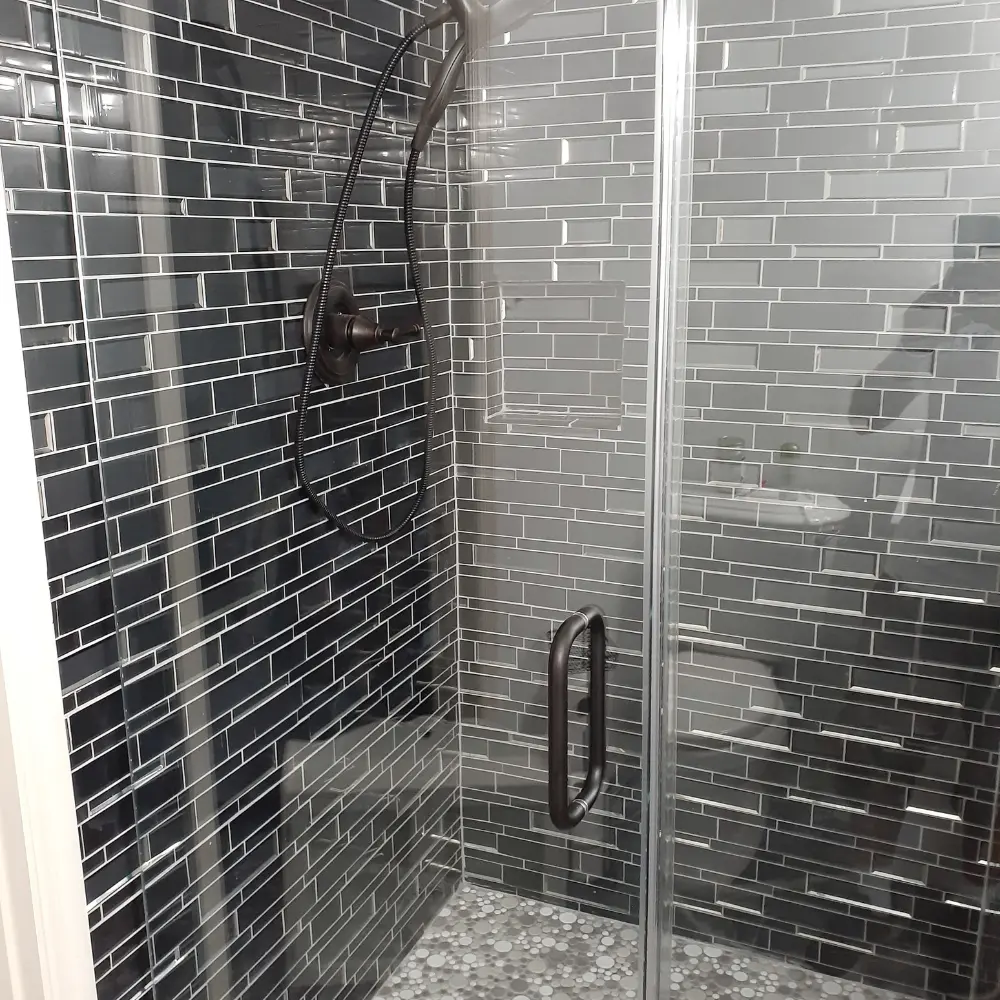 Glass-enclosed shower with dark gray subway tile